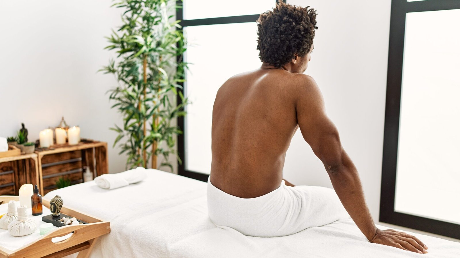Young african american man sitting on massage board at beauty center